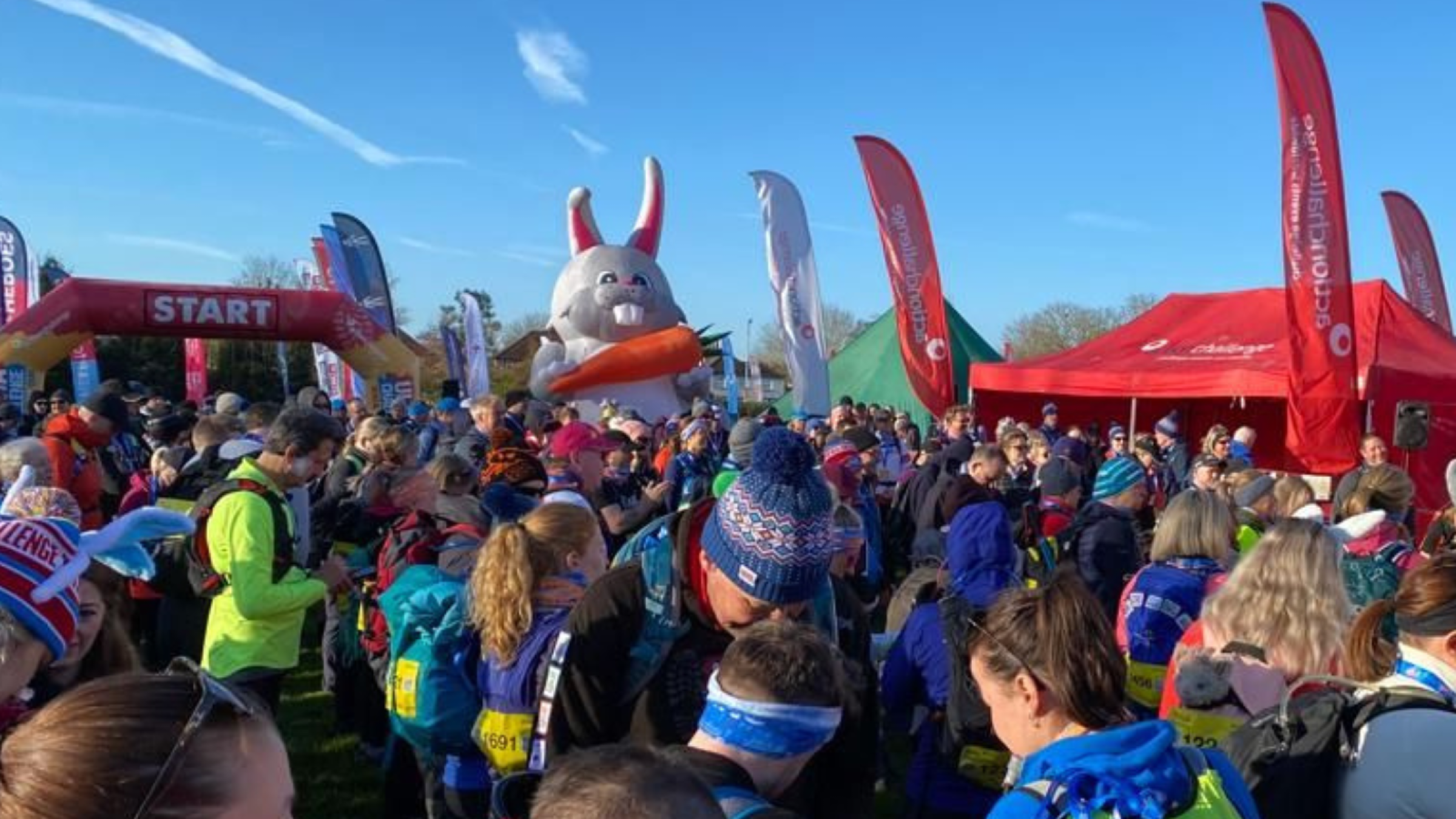 A crowd of people at the start line with a giant bunny in the background