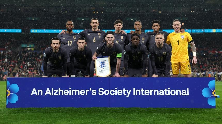 The England men's team lined up for a photo with a banner that reads 'An Alzheimer's Society International'